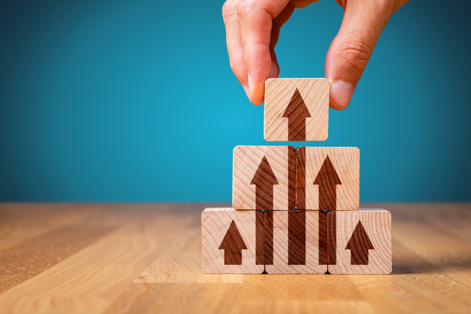 Abstract image to represent leadership: arrows pointing up drawn on wooden blocks.