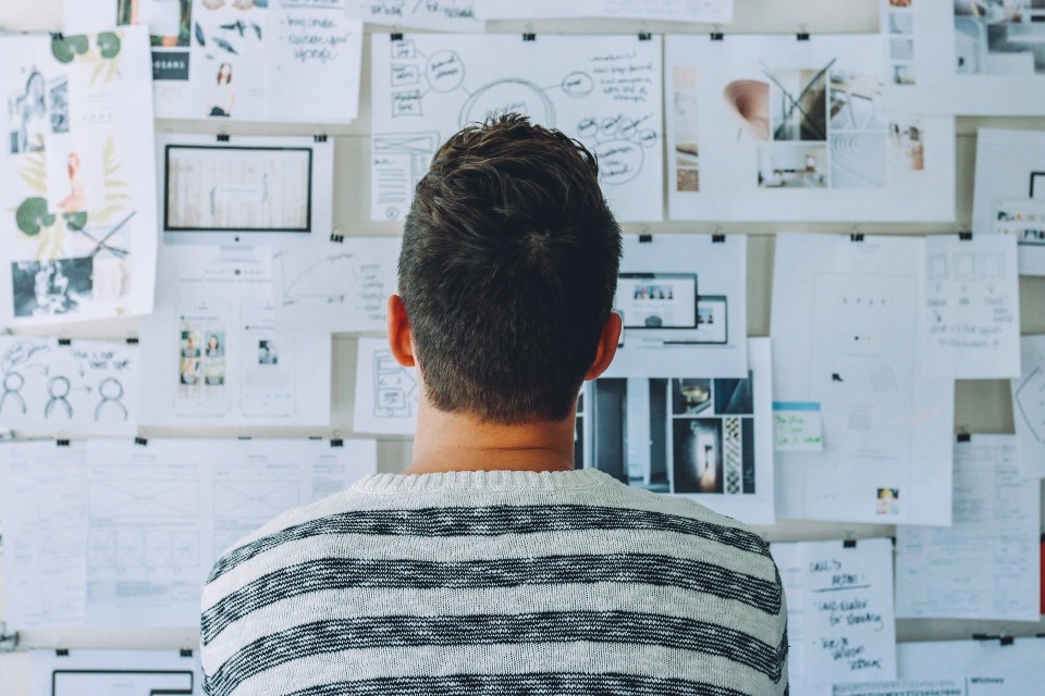 Man looking at papers and notes on the wall.