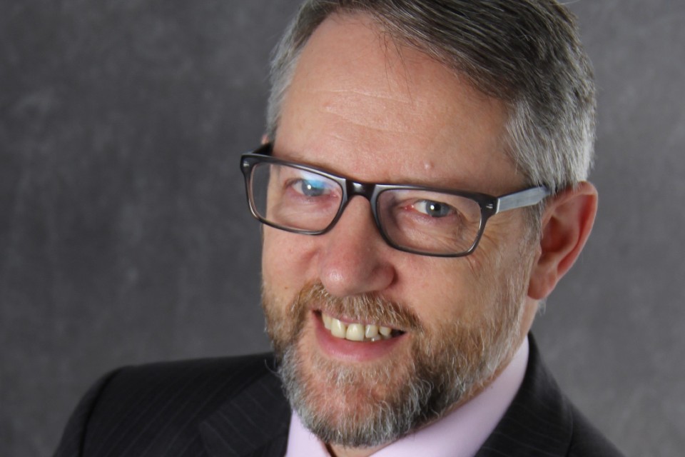 Headshot of a man in glasses smiling.