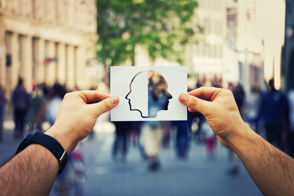 A man holding a paper on the street with an image of a human head symbolising behavioural change.