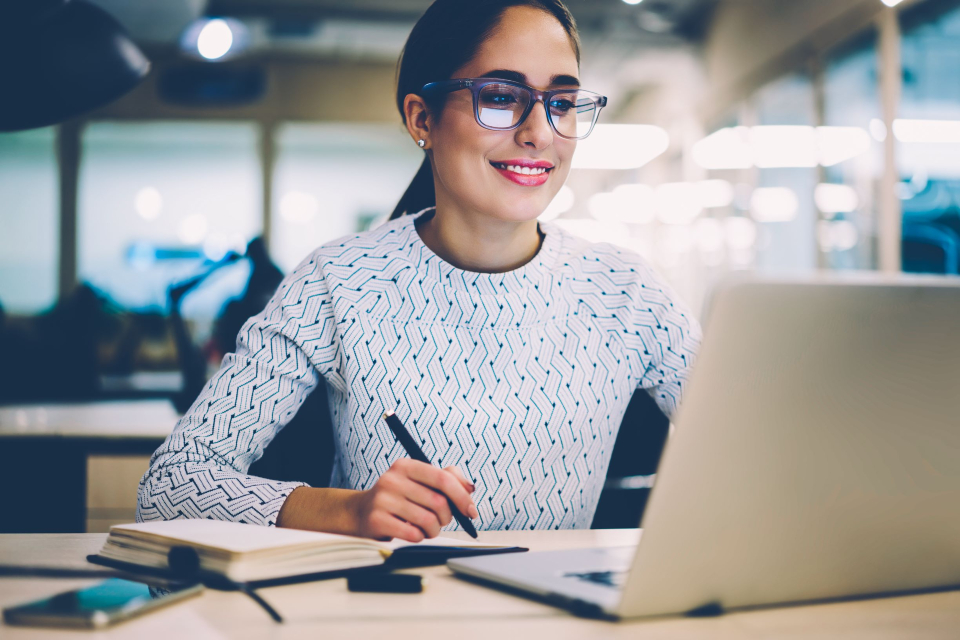 woman smiling working on a laptop.
