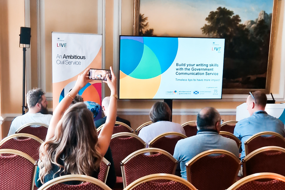 Image of audience at CS Live presentation. 1 attendee capturing an image with their smart phone