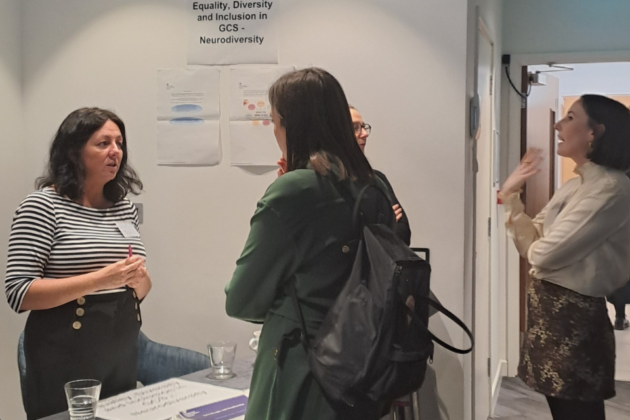 Linda Murray standing at the Neurodiversity stall talking to an attendee from the GCS New Members' Event