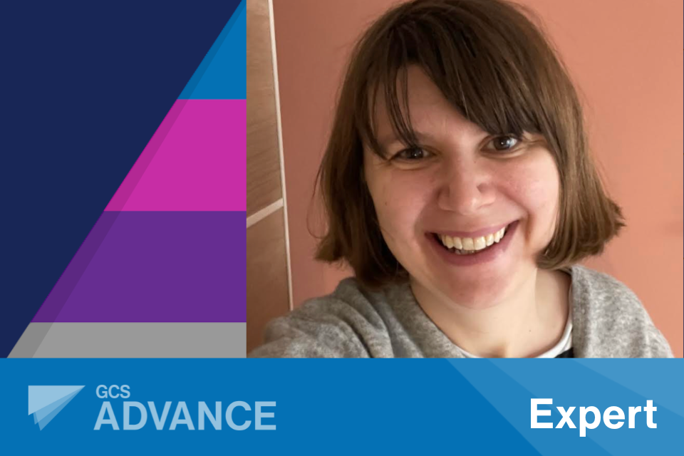 Selfie-style picture of Lizzie Harris, from Department for Transport and Advance Expert graduate, with the 'Advance' logo and the word 'Expert' on a blue coloured banner layered over the top and the 'Advance' five tiered coloured pyramid behind on a dark navy background