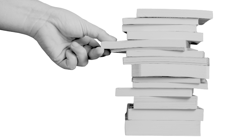 Hand pulling out a notebook from a pile of notebooks in grey on a white background