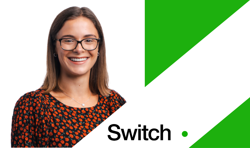 Ruby standing smiling to the camera. The background is a bright green and to the right is a white tilted rectangle with the 'Switch' logo.