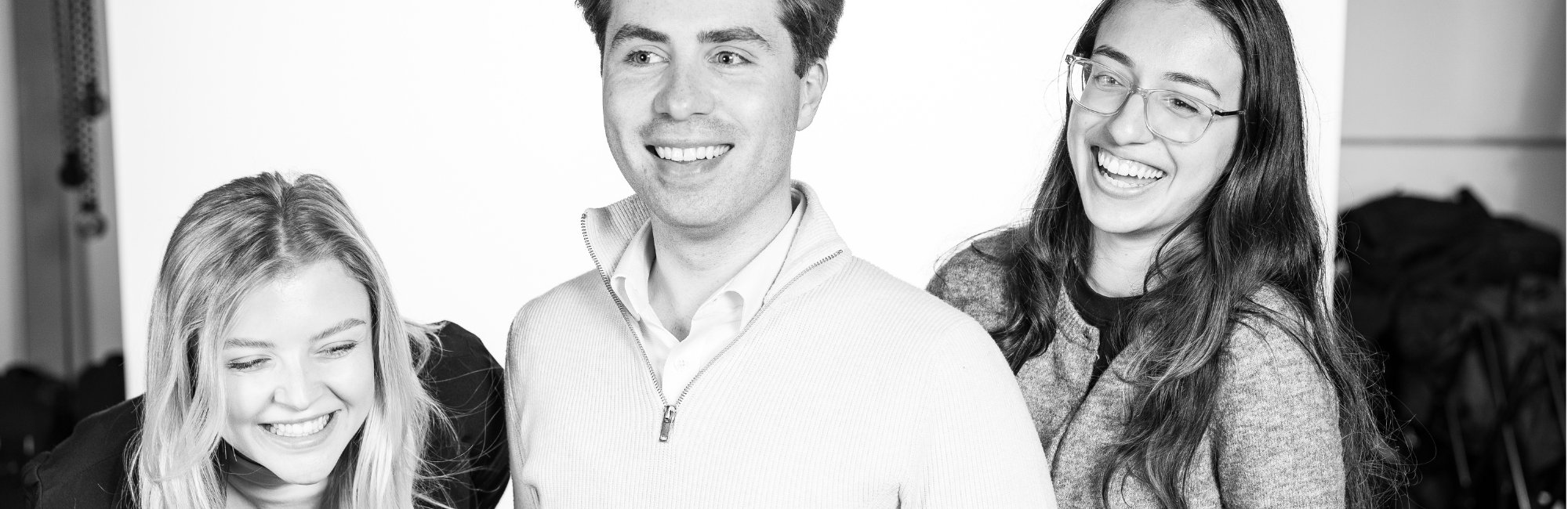 Three people smiling and laughing in a photo studio.