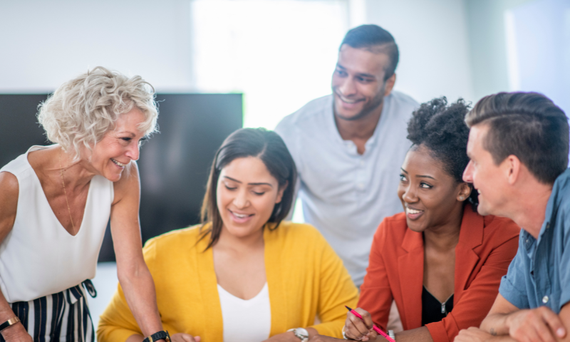A group of five people are gathered together talking.